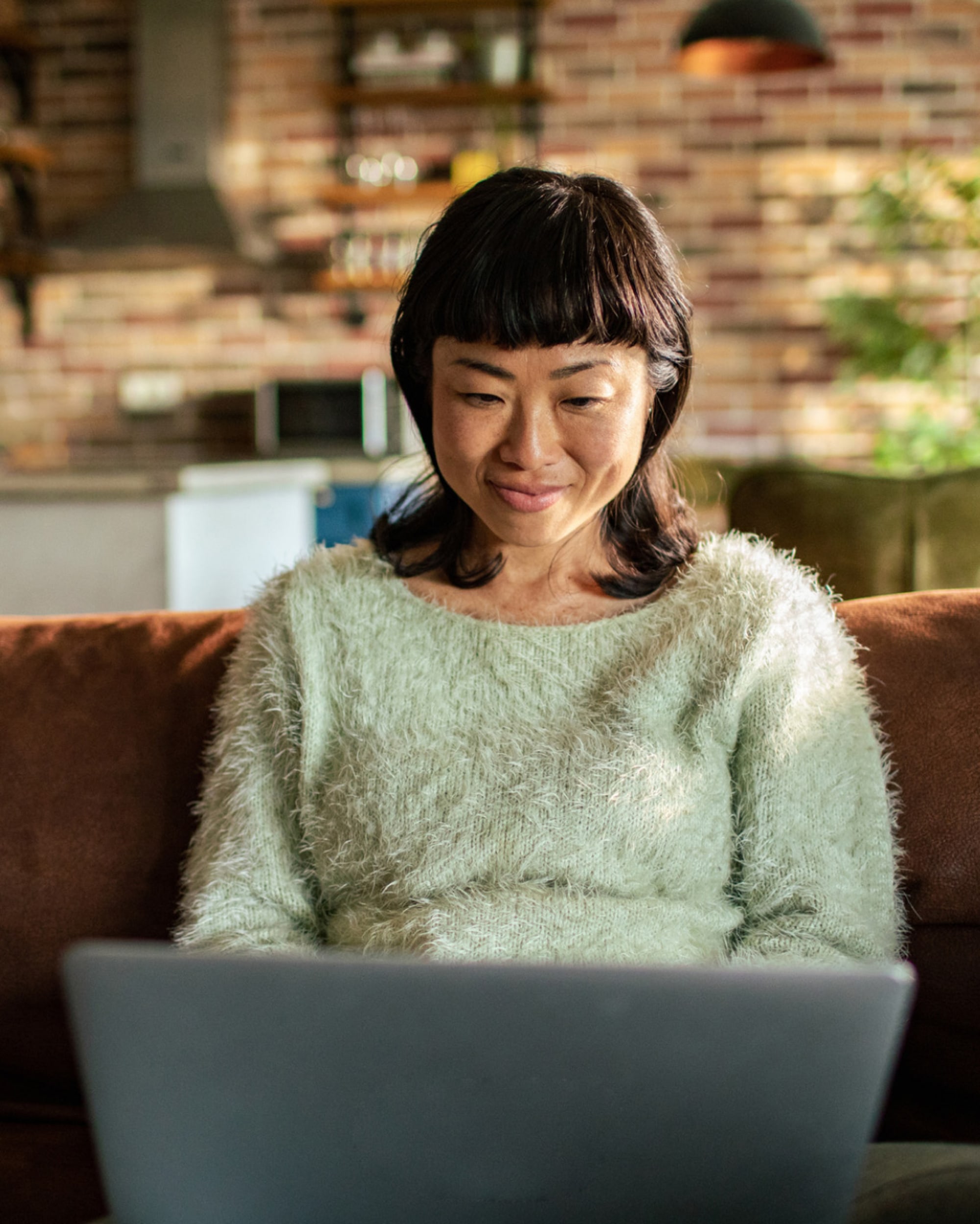  A woman in a sweater is using a laptop